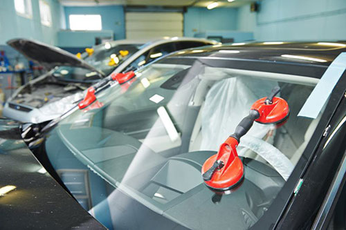 two cars in body shop with windshield being installed